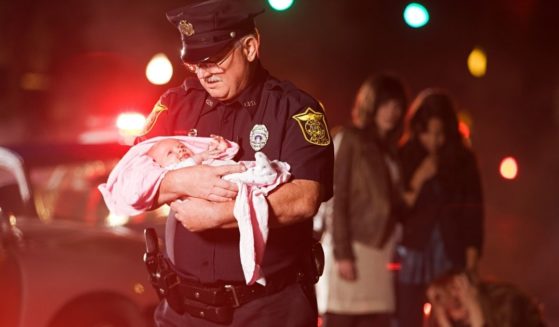 This stock image shows an officer rescuing a baby from the scene of a car accident.