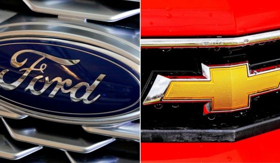 At left, the Ford logo is seen on the grill of a car on display at the Pittsburgh Auto Show on Feb. 15, 2018. At right is the Chevrolet logo on the grill of a 2013 Camaro SS.