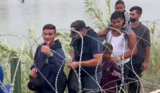 A group of illegal immigrants is filmed after crossing into the U.S. They are in good spirits, with one holding up a "thumbs up" to the camera, while in the background others can be seen crossing the river.