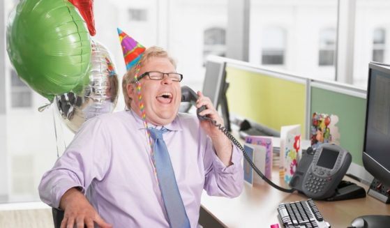Business man laughing into phone at work.