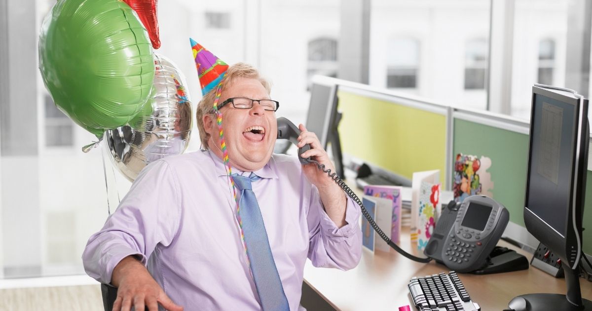 Business man laughing into phone at work.