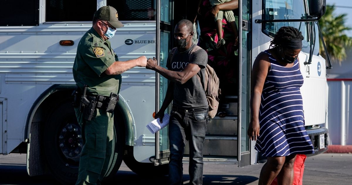 Ernso Bogui fist bumps a United States Border Patrol agent after departing a bus. Bogui and others on the bus were released from custody upon crossing the Texas-Mexico border in Del Rio, Texas, on Sept. 22, 2021.