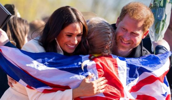 Prince Harry and Meghan Markle, Duke and Duchess of Sussex, hug Lisa Johnston, a former army medic and amputee, who celebrated with her medal at the Invictus Games in The Hague, Netherlands, Sunday. Harry told child journalists at the event that his goal is to work to create 'a more equal world.'