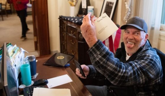 Richard Barnett holds a piece of mail as he sits inside the office of Speaker of the House Nancy Pelosi after protesters breached the U.S. Capitol in Washington, D.C., on Jan. 6, 2021.