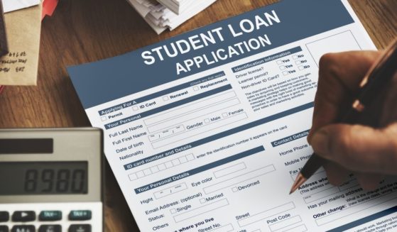 Hand filling out a student loan application form.