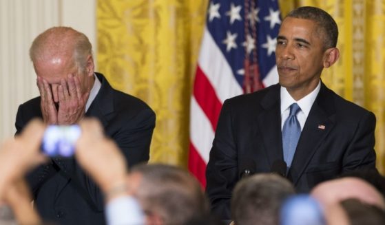 President Joe Biden puts his face in his hands in reaction to a heckler while standing next to former President Barack Obama at the White House in June.