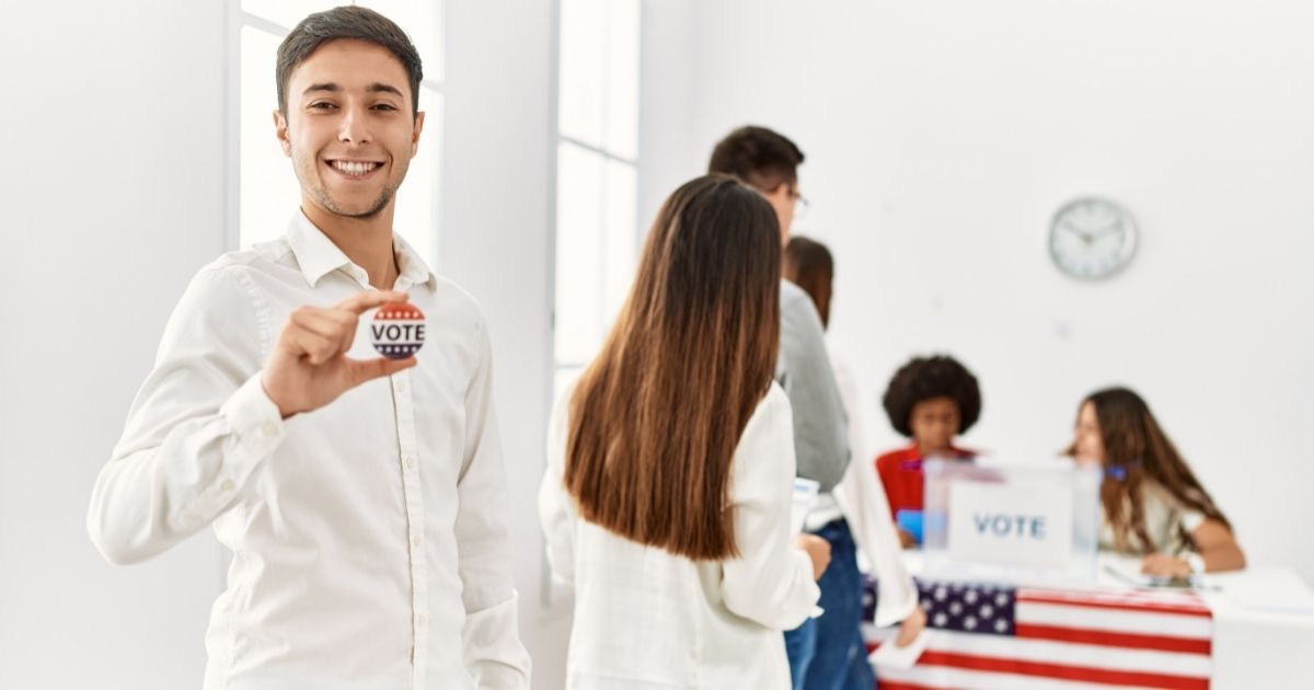 This stock photo shows young voters, in the 18-29 demographic, encouraging others to vote in the U.S. election, with one young man holding up a pin that reads "Vote."