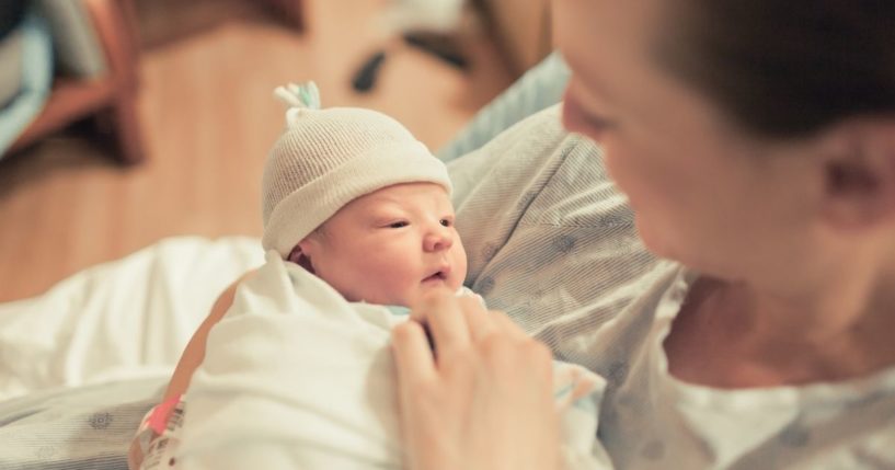 A mother holds her newborn baby in this stock image.