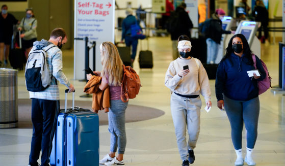 ravelers wearing masks intended to help stop the spread of the coronavirus move about a terminal at the Philadelphia International Airport on April 19, 2022.
