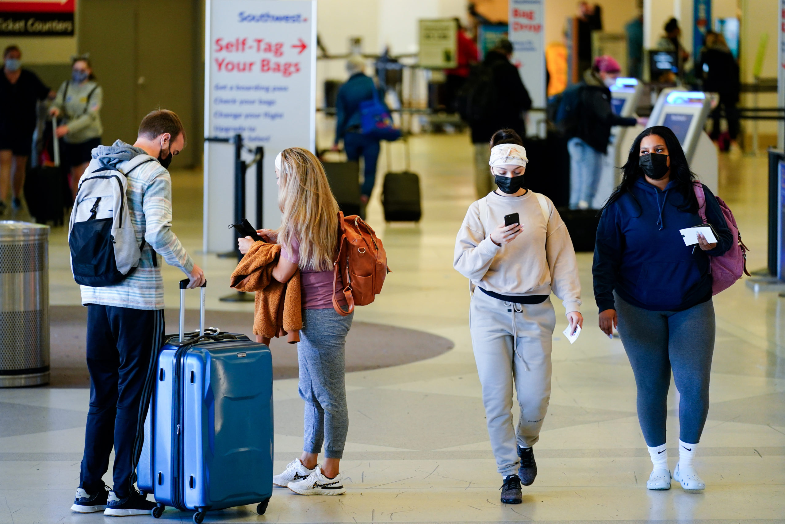 ravelers wearing masks intended to help stop the spread of the coronavirus move about a terminal at the Philadelphia International Airport on April 19, 2022.