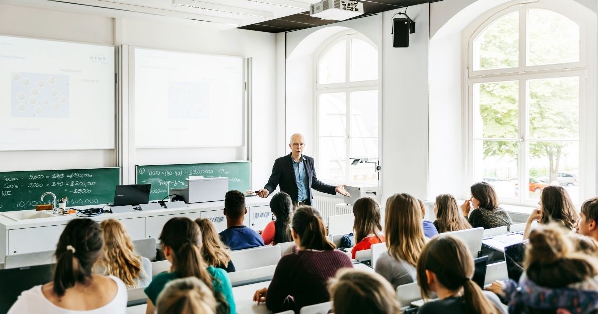 A college professor gives a lecture in the above stock image.
