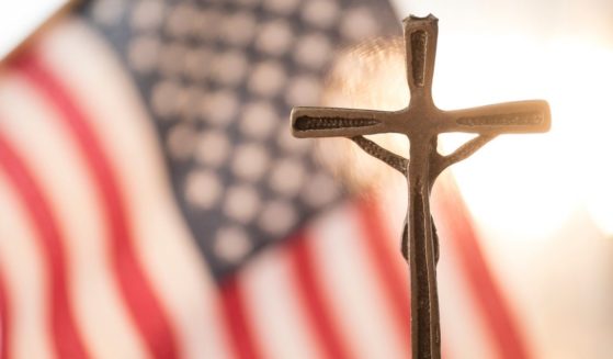 The American flag and a cross are seen in the above stock image.
