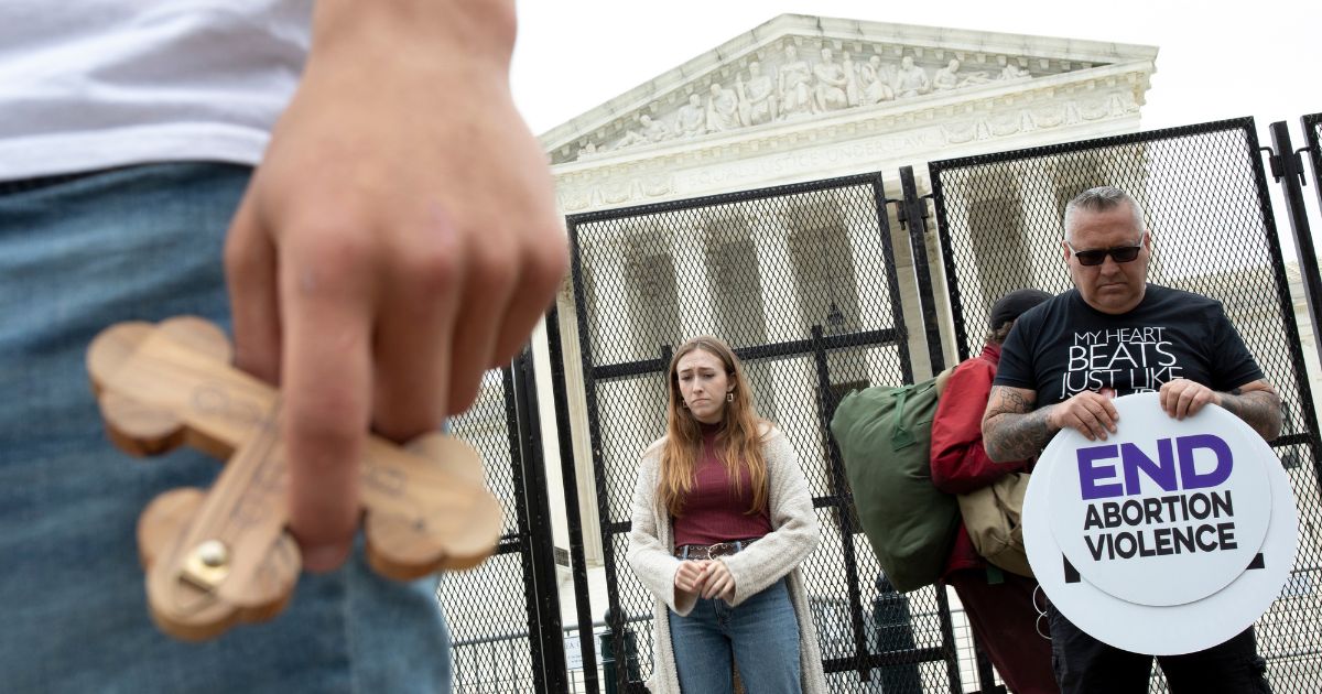 Nate Darnell, left, holds a cross as pro-life activists pray outside the Supreme Court in Washington on Thursday.