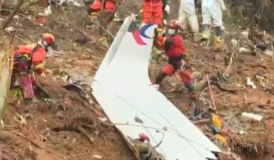 This screengrab taken on March 24 from video by state broadcaster China Central Television shows rescue teams with a piece of the fuselage as they continue their search at the site of where a China Eastern passenger jet crashed onto a mountainside near Wuzhou City in China's southern Guangxi region.