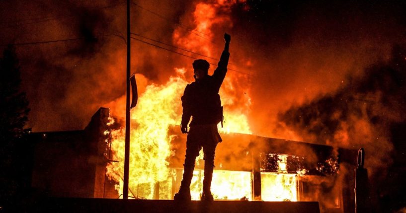 A demonstrator stands in front of a burning building during a riot in Minneapolis on May 29, 2020, following the death of George Floyd in police custody.