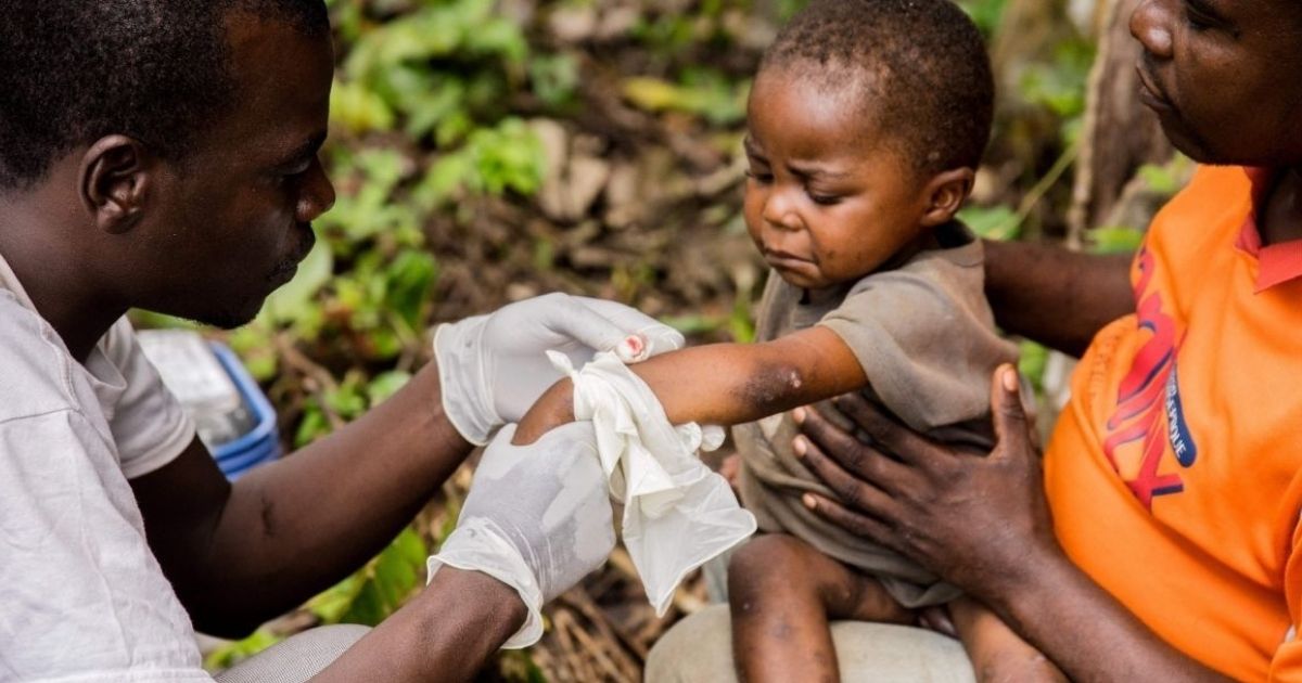 A child infected with monkeypox sits on his father's lap while receiving treatment in the Central African Republic village of Zomea Kaka in 2018.