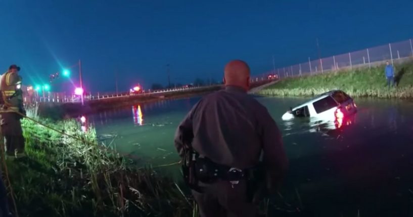 Responders work to free the driver trapped inside her sinking vehicle.