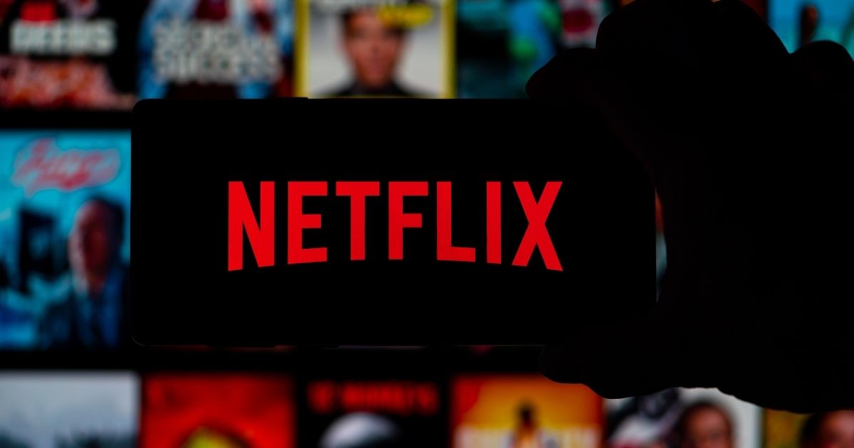 The Netflix logo is displayed on a cellphone in the above stock image.