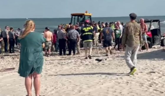 First responders are pictured at the scene of a New Jersey beach where Levi Caverly, 18, and his 17-year-old sister became trapped in a 10-foot hole they had dug at the beach. Unfortunately, by the time they reached the siblings Levi had not survived being buried alive.