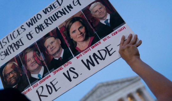 A pro-abortion demonstrator in Washington, D.C., holds a sign with the faces of Supreme Court Justices who it is believed are poised to overturn Roe v. Wade based on a leaked draft of a majority opinion.