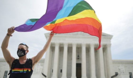 A man holds an LGBT flag in front of the U.S. Supreme Court in Washington, D.C., on June 15, 2020.