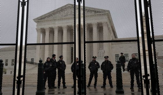 Police officers stand watch behind a fence surrounding the U.S. Supreme Court on Saturday in Washington, D.C.