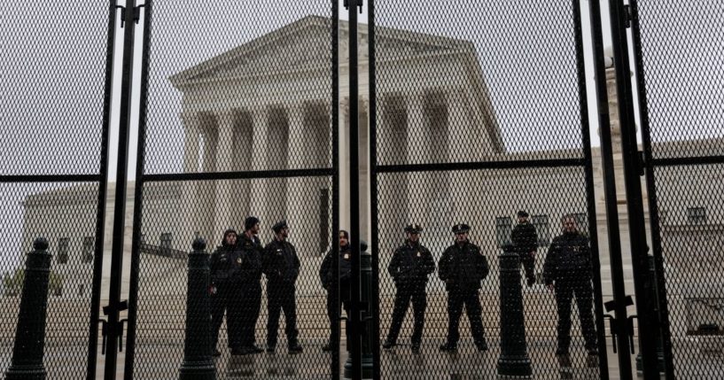 Police officers stand watch behind a fence surrounding the U.S. Supreme Court on Saturday in Washington, D.C.
