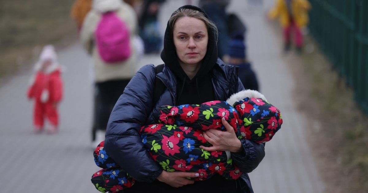 A mother carrying an infant arrives in Poland from war-torn Ukraine on March 4 near Medyka, Poland.