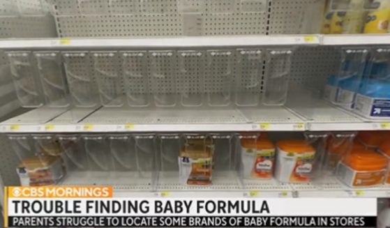 Nearly bare shelves where baby formula should be found in a store.