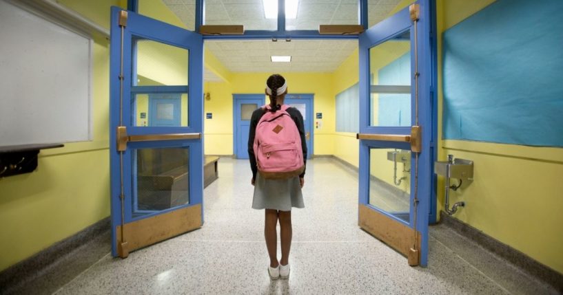 A girl stands in a school hallway in this stock image.