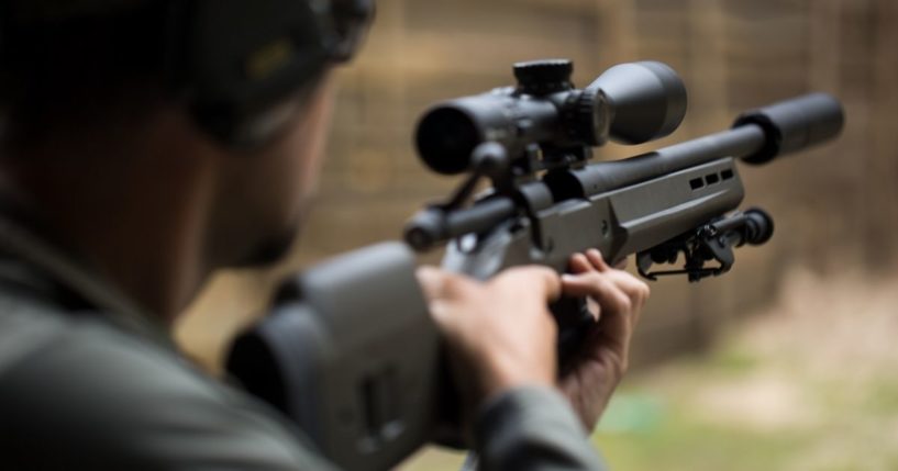 A man shoots a rifle in this stock image.