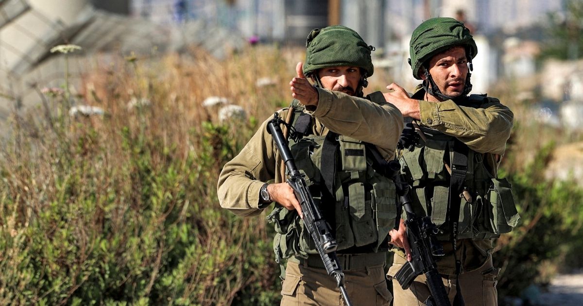 Israeli soldiers confront journalists approaching the Israeli-controlled Hawara checkpoint on Tuesday.