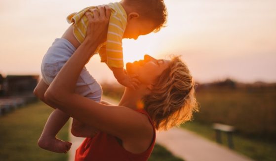 A mother lifts up her child in this stock image.