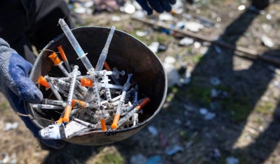 A volunteer collects syringes from a homeless encampment on March 12 in Seattle, Washington.