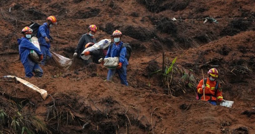 Emergency workers carry away debris near the China Eastern crash site on March 24.