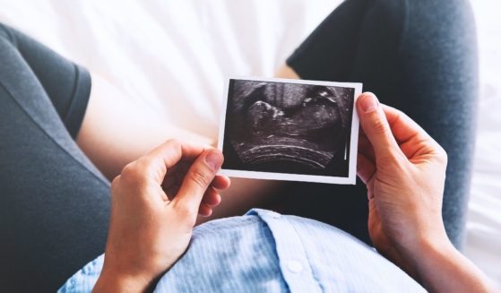 A pregnant woman looks at an ultrasound photo in this stock image.