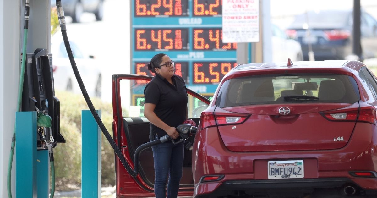 A woman pumps gas into her car at a gas station