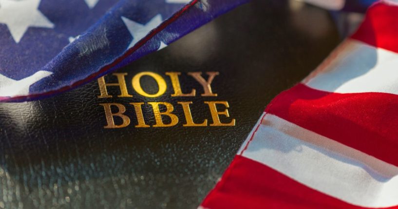 A Bible draped in an American flag is seen in the above stock image.
