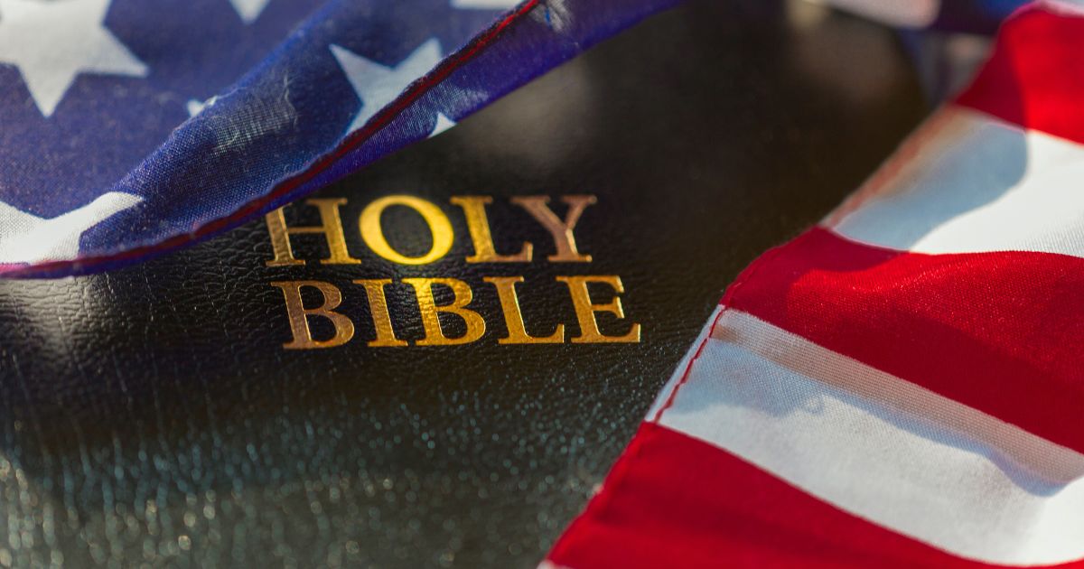 A Bible draped in an American flag is seen in the above stock image.