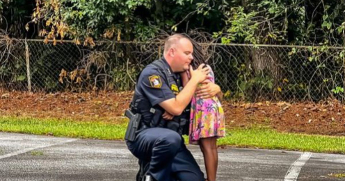 David Snively, interim chief of the Morrow, Georgia, Police Department, takes a moment from his duty to comfort a little girl after an arrest was made.