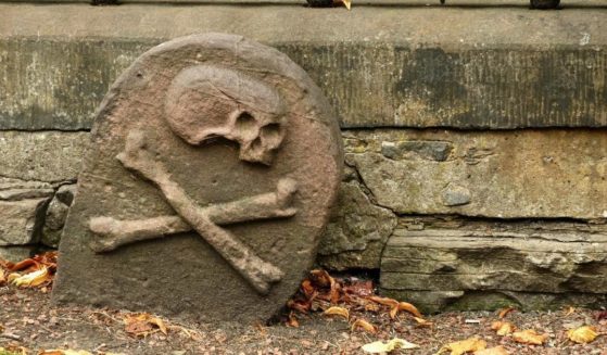 A grave marked with a skull symbol is seen in this stock image.