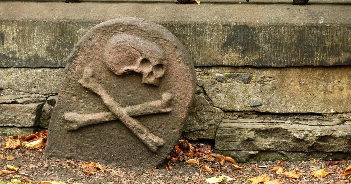 A grave marked with a skull symbol is seen in this stock image.