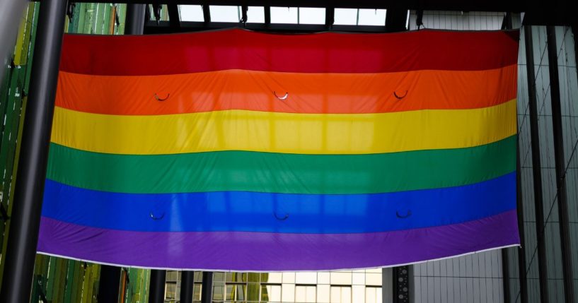 An LGBT flag hangs between two buildings in downtown Seattle.
