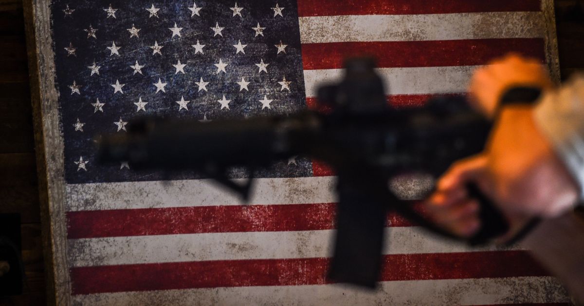 An instructor holds an AR-15 rifle with a U.S. flag in the background during a shooting class at the Boondocks Firearms Academy in Jackson, Mississippi, on Sept. 26, 2020.