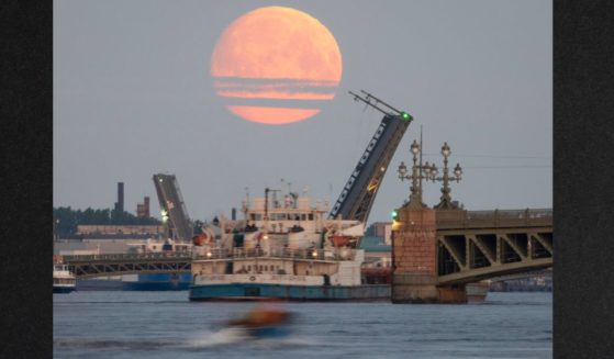 A cargo ship travels past as drawbridges rise above the Neva River, with the moon in the sky, in St. Petersburg, Russia, in this file photo from May 2021. The U.S. has been quietly urging U.S. companies to buy and carry Russian fertilizer and other products, but the companies are reluctant, fearing the prospect of costly sanctions.