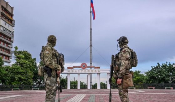 Russian servicemen look at the Russian national flag in central Melitopol, Ukraine, on June 14. Ukranian officials report Russian soldiers have been stealing Ukranian crops and selling them in other countries.