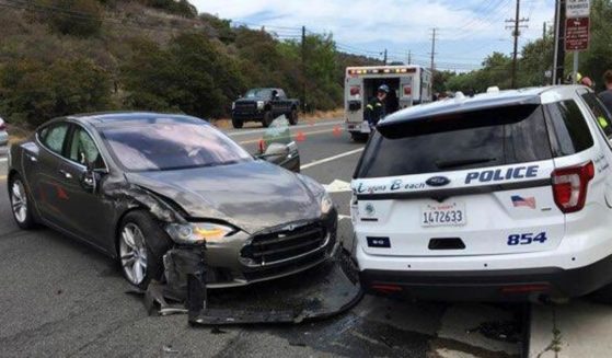 This photo provided by the Laguna Beach Police Department shows a Tesla sedan, left, that crashed into a parked police cruiser on May 29, 2018, in Laguna Beach, California.