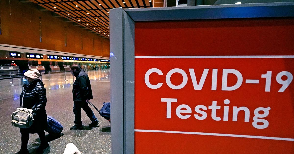 Travelers pass a sign near a COVID-19 testing site in Terminal E at Logan Airport in Boston on Dec. 21, 2021.