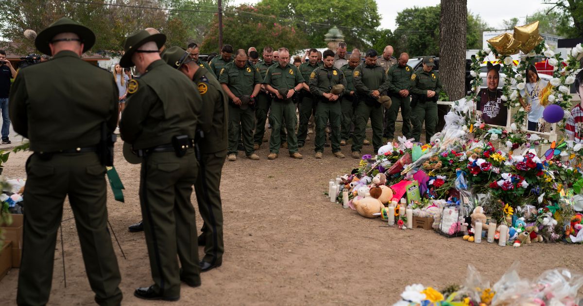 Border Patrol agents pray during a visit Tuesday to the memorial at Robb Elementary School in Uvalde, Texas.