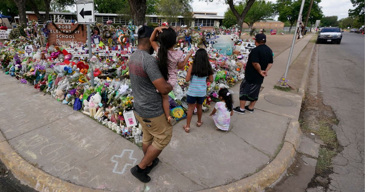 Mourners visit a memorial at Robb Elementary School created to honor the victims of the May 24 massacre in Uvalde, Texas.